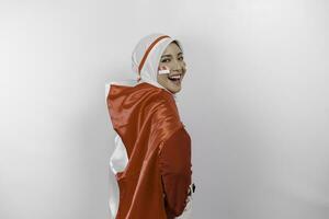 Lycklig leende indonesiska muslim kvinna bär röd topp och vit hijab innehav Indonesiens flagga till fira indonesien oberoende dag. isolerat förbi vit bakgrund. foto