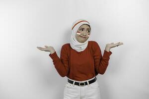 en omtänksam ung muslim kvinna bär vit hijab och röd topp är förvirra mellan val bredvid henne, isolerat förbi vit bakgrund. Indonesiens oberoende dag. foto