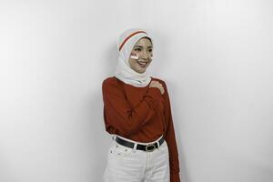 skön asiatisk kvinna bär röd topp och vit hijab ger honnör fira indonesiska oberoende dag på augusti 17 isolerat över vit bakgrund foto