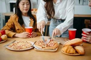 Lycklig raser vänner chattar, äter pizza tillsammans, har små fest på Hem foto