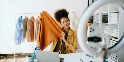 mode bloggare begrepp, ung afrikansk kvinnor försäljning kläder på video streaming.startup små företag sme, använder sig av smartphone eller läsplatta foto