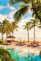 vackert lyxigt paraply och stol runt utomhuspoolen på hotellet och resort med kokospalmer på solnedgången eller soluppgångshimlen
