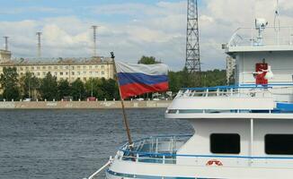 silver- viska kryssning fartyg på neva flod vägbank, vattenväg, med historisk byggnader. i de förgrund de flagga av de ryska federation foto