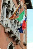 italiensk och europeisk flaggor vinka på balkong i offentlig fyrkant foto