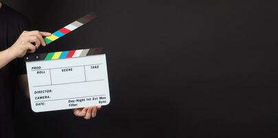 clapperboard eller film kläpp styrelse i man ge den är Begagnade i video produktion och filma industri på svart bakgrund. foto