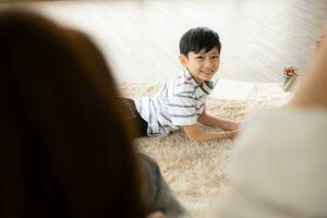 en pojke och en dotter från ett asiatisk familj. de barn är har roligt i de konst av teckning. mamma och pappa haft spelar spel på de bärbar dator. foto