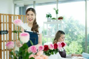 två asiatisk kvinna blomsterhandlare arbetssätt på blomma affär med bärbar dator. foto