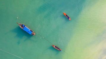 Flygfoto ovanifrån, fiskebåt, turistbåt som flyter på ett grunt klart hav, vackert ljusblått vatten i havet foto