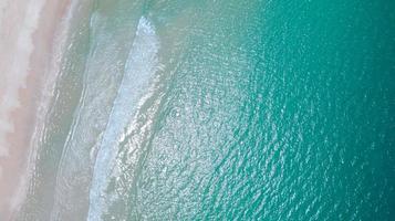 Flygfoto över stranden med smaragdblått vatten och vågskum på tropiskt hav