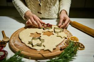 jul och ny år firande traditioner. traditionell festlig mat tillverkning, familj kulinariska. kvinna skärande småkakor av rå pepparkaka deg foto