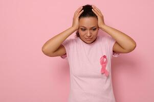 oktober bröst cancer medvetenhet månad, kvinna i rosa t- skjorta med rosa band för stödjande människor levande och sjukdom, innehav händer på huvud, isolerat på rosa bakgrund med kopia Plats för text foto