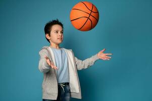 förtjusande pojke barn kasta en boll medan spelar basketboll foto