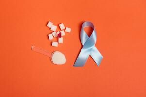 ren raffinerad vit socker kuber med blod släppa och blå satin band, symbol av värld diabetes medvetenhet dag 14 november. isolerat över färgad orange bakgrund, kopia Plats för medicinsk annons. platt lägga foto