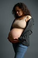 attraktiv gravid kvinna försiktigt strök henne stor mage, upplever underbar känslor känsla bebis rör sig. graviditet foto