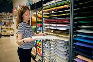 självsäker kvinna välja Färg papper i brevpapper affär. försäljare Arbetar på merchandising i skola brevpapper Lagra foto
