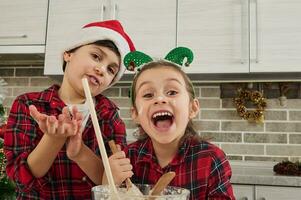glad söt barn unna sig, ha roligt tillsammans i de Hem kök, framställning deg för jul kaka och småkakor. de barn sig själva är i de kök foto