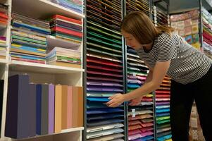 caucasian kvinna försäljning chef ordnar mång färgad kartong papper ark på detaljhandeln hyllor i en kreativ konst Lagra foto