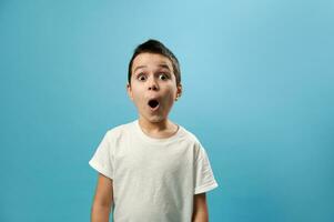 chockade pojke Framställ med öppnad mun uttrycker överraskning på blå bakgrund med kopia Plats foto