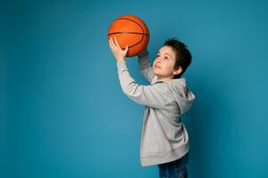 isolerat porträtt på blå bakgrund av en stilig pojke spelar basketboll foto