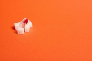 värld diabetes dag medvetenhet begrepp, 14 november. ren raffinerad vit socker kuber med blod släppa, isolerat över färgad orange bakgrund med kopia Plats för medicinsk reklam foto