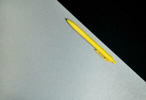 topp se . platt lägga sammansättning av kontor verktyg. gul penna och del av svart papper på en grå bakgrund foto