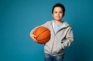 porträtt av ett förtjusande sportig barn innehav en boll för spelar basketboll i hand foto