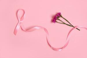 platt lägga av en lång rosa satin band, var ett slutet är ändlös och blommor. bröst cancer medvetenhet, medicinsk begrepp isolerat på rosa bakgrund med kopia Plats. oktober medvetenhet månad kampanj. foto