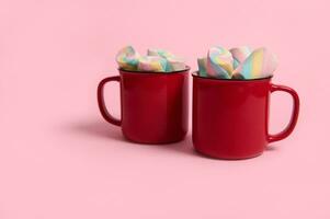 marshmallows i röd koppar av varm choklad dryck isolerat över rosa pastell bakgrund med kopia Plats för jul annons foto