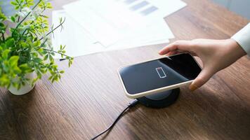 laddning mobil telefon batteri med trådlös laddning enhet i de tabell. smartphone laddning på en laddning vaddera. mobil telefon nära trådlös laddare modern livsstil teknologi begrepp. foto