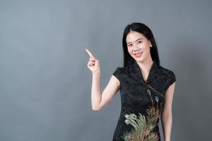 vacker ung asiatisk kvinnakläder kinesisk traditionell klänning med handen presenterar på sidan foto