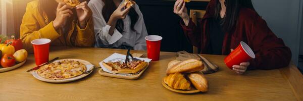 grupp av ung vänner äter pizza på Hem och har roligt foto