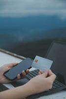 uppkopplad betalning, ung kvinna innehav kreditera kort och skriver på bärbar dator foto
