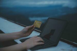uppkopplad betalning, ung kvinna innehav kreditera kort och skriver på bärbar dator foto