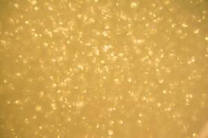 guld glitter bakgrund. skimrande fläck fläck lampor bokeh skinande guld ljus bakgrund. foto