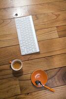 en tangentbord, mus och kaffe kopp på en trä- tabell foto