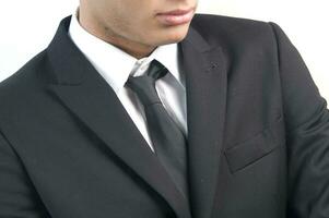 en man i en svart kostym och slips ser ner foto