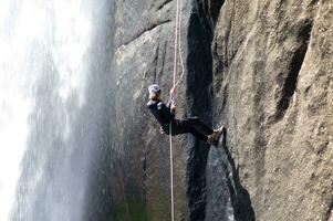 en person på en rep klättrande upp en vattenfall foto