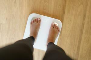 tappa bort vikt. fett diet och skala fötter stående på elektronisk skalor för vikt kontrollera. mått instrument i kilogram för diet. foto