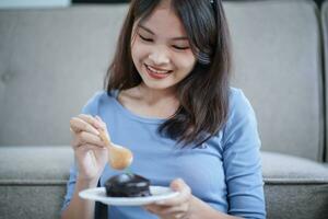 skön asiatisk kvinna äter gott choklad kaka. tonåring flicka äter de kaka. foto