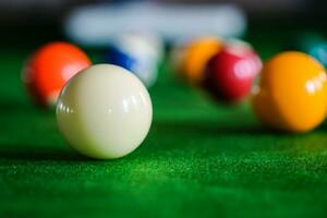 mannens hand och kö ärm spelar snooker spel eller framställning siktar till skjuta slå samman bollar på en grön biljard tabell. färgrik snooker bollar på grön fris. foto