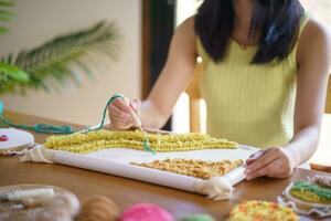 stansa nål. asiatisk kvinna framställning handgjort hobby stickning i studio verkstad. designer arbetsplats handgjort hantverk projekt diy broderi begrepp. foto