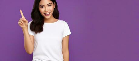 underbar asiatisk flicka med mörk hår vit tank topp leende och gestikulerar mot tömma Plats för reklam på lila bakgrund foto