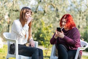 flickvänner som använder smartphone och röker cigarett