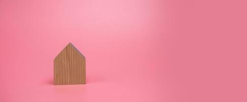 trä hus modell på rosa bakgrund , hantera fast egendom investering begrepp, baner bakgrund foto