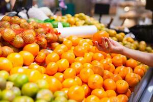 kvinna välja apelsiner i matvaror Lagra. begrepp av friska mat foto