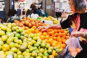 senior kvinna handla apelsiner på matvaror Lagra foto