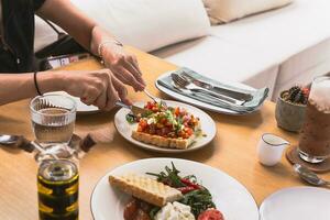 kvinna händer håll kniv och gaffel skärande bruschetta appitizer på de tallrik. foto