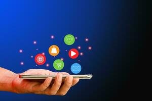 företag och teknologi begrepp. hålla handen smartphone eller mobil telefon med social media och social nätverk ikoner på blå bakgrund. foto