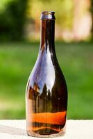 en brun glas flaska Sammanträde på en trä- tabell foto