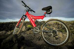en röd cykel är parkerad på en klippig kulle foto